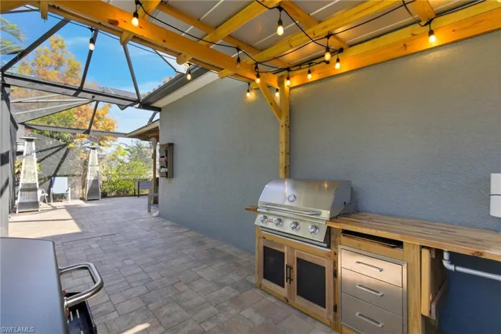 View of patio with glass enclosure, a sunroom, and an outdoor kitchen