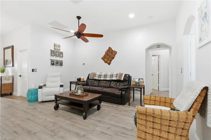 Living area featuring arched walkways, light wood finished floors, a ceiling fan, and recessed lighting
