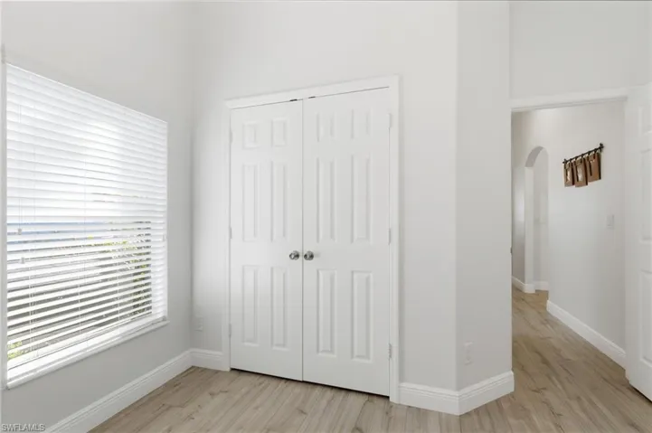 Unfurnished bedroom with light wood-style flooring, a closet, and arched walkways