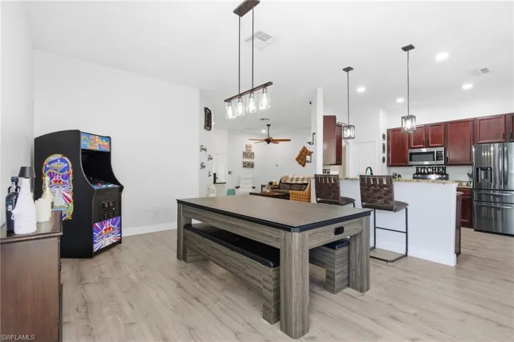Kitchen with appliances with stainless steel finishes, ceiling fan, decorative light fixtures, a peninsula, and light wood-style flooring