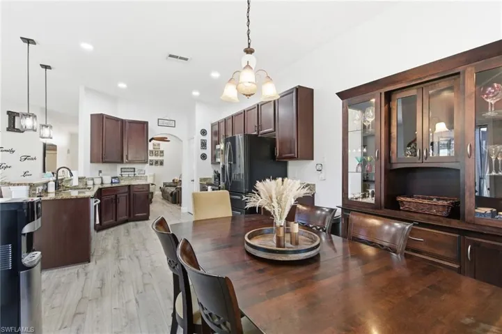 Dining space with arched walkways, a chandelier, light wood-style floors, and recessed lighting