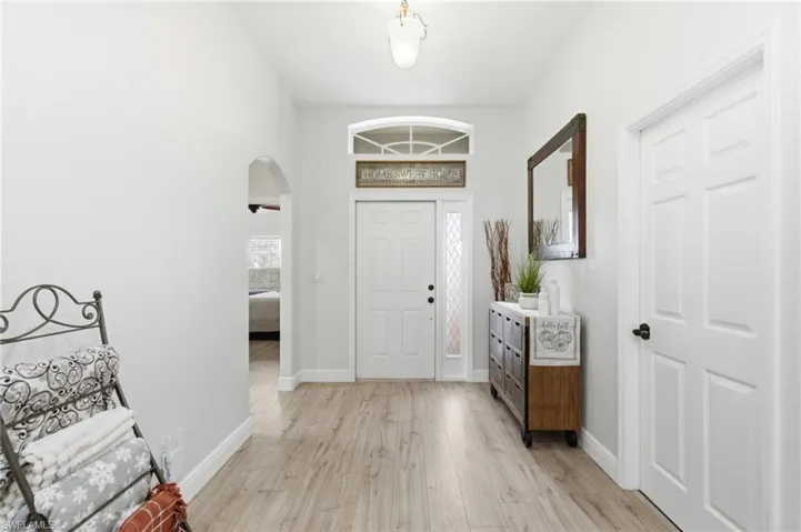 Foyer entrance with light wood-type flooring, arched walkways, and healthy amount of natural light