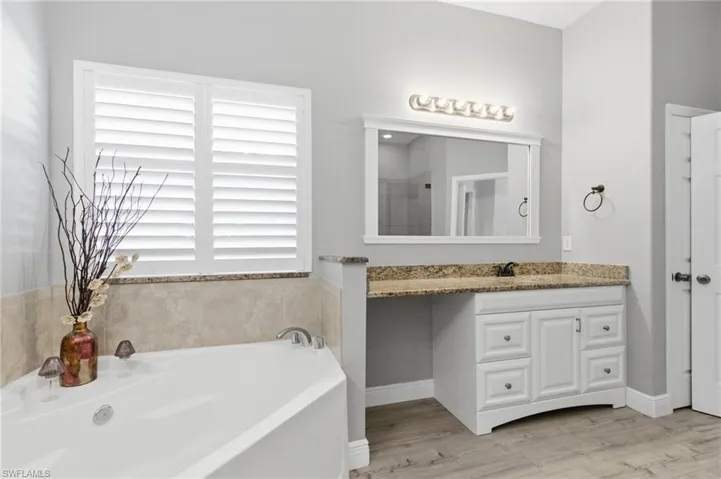 Full bath featuring vanity, a bath, a shower stall, and light wood-type flooring