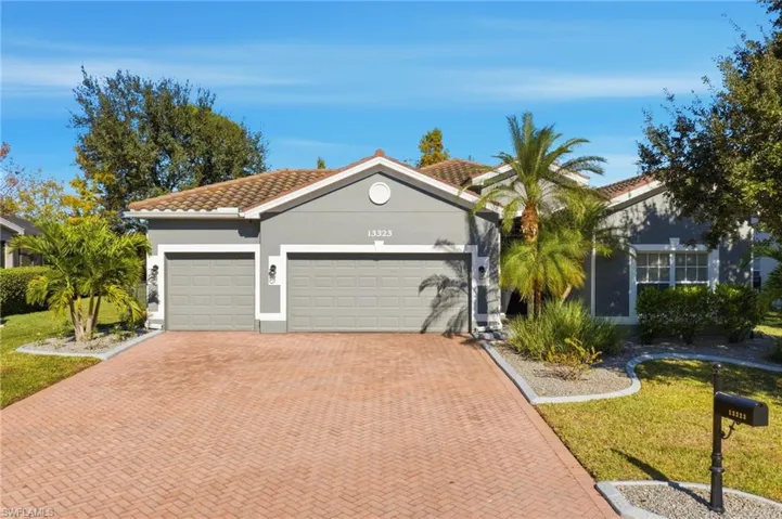 Mediterranean / spanish house featuring a tiled roof, stucco siding, a front lawn, decorative driveway, and a garage