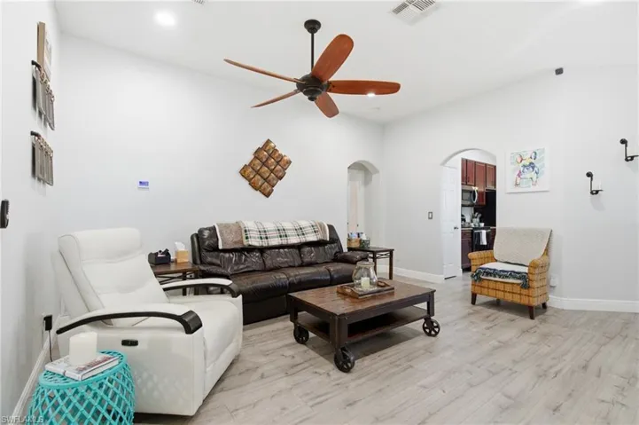 Living room featuring arched walkways, a ceiling fan, and light wood-style floors