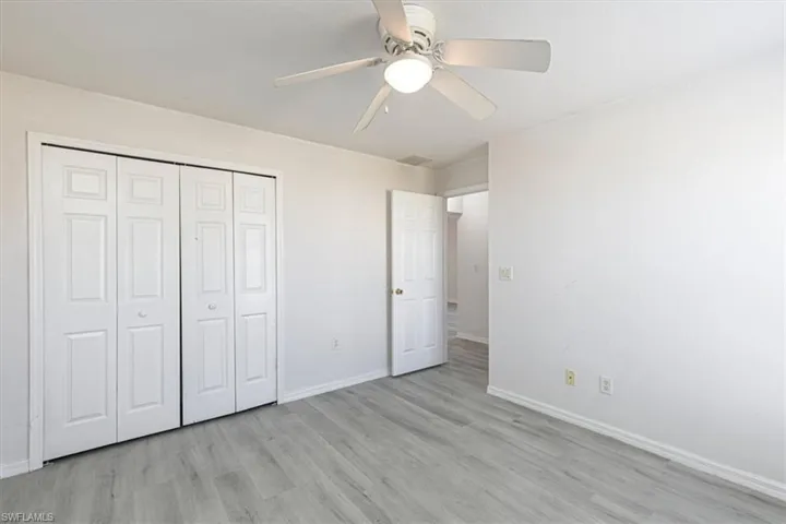 Unfurnished bedroom with light wood-type flooring, ceiling fan, and a closet