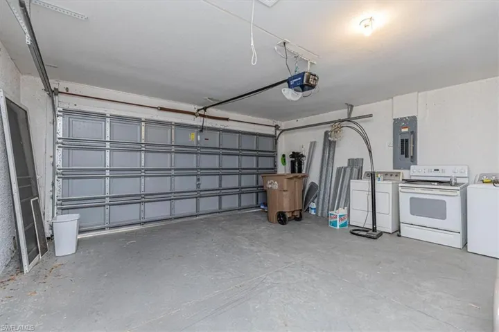 Garage with washer and clothes dryer, electric panel, and a garage door opener