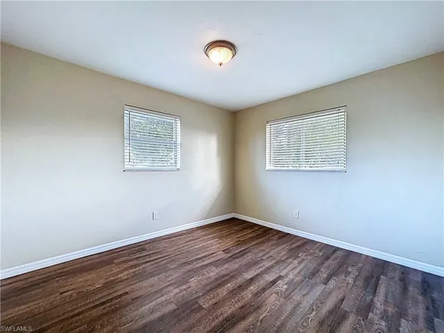 Spare room with dark wood finished floors and baseboards