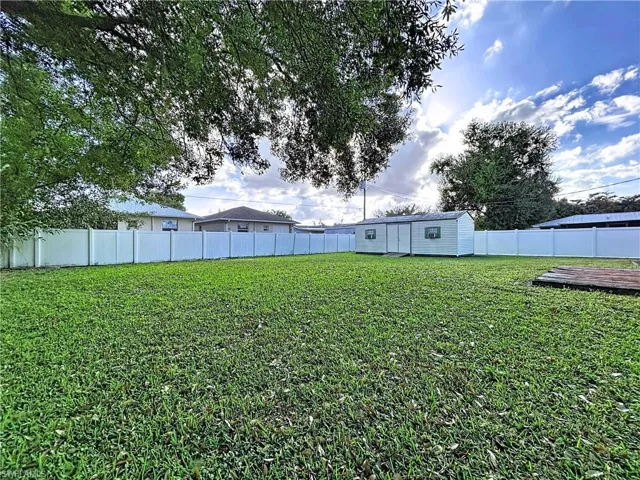 Fenced backyard featuring a shed