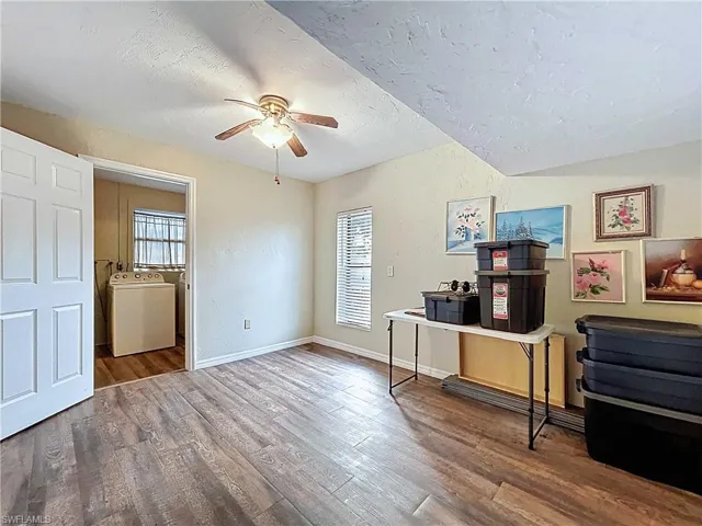 Office area with wood-look vinyl plank floors, healthy amount of natural light, a textured wall and ceiling, and ceiling fan