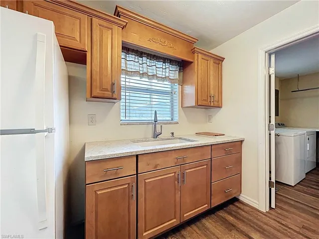 Kitchen features a window over the sink, built-in cabinets, same vinyl wood-plank flooring and light stone countertops