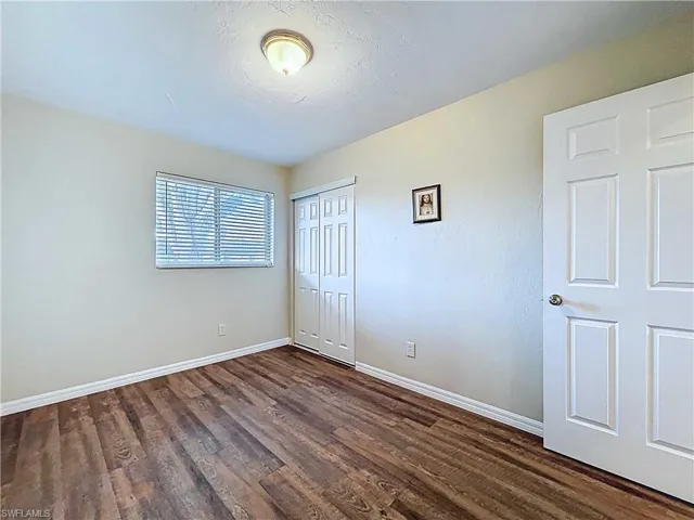 Unfurnished bedroom featuring dark wood finished floors, a closet, and a textured ceiling
