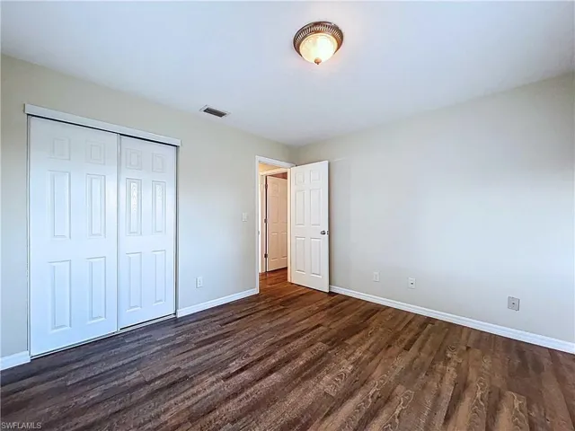 Unfurnished bedroom featuring a closet and dark wood finished floors