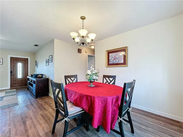 Dining area featuring dark wood-style flooring, a chandelier, and a textured ceiling