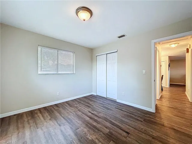 Unfurnished bedroom with dark wood-style flooring and a closet