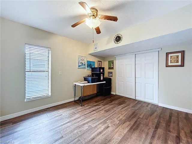 Office space/ bedroom featuring same wood-look vinyl plank flooring and ceiling fan