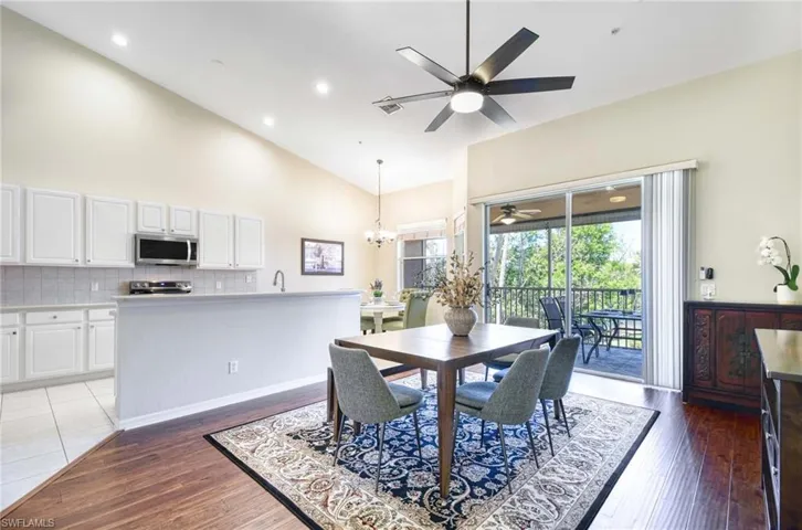 Dining area featuring ceiling fan, high vaulted ceiling, a chandelier, light wood-style floors, and recessed lighting