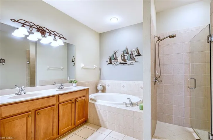 Full bath with tile patterned flooring, a shower stall, a bath, and double vanity