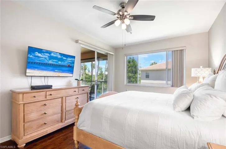 Bedroom featuring access to exterior, dark wood-style flooring, a ceiling fan, and baseboards