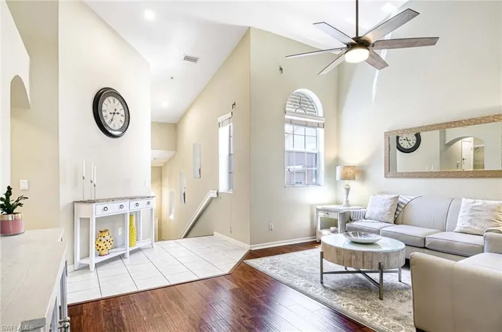 Living area featuring hardwood / wood-style floors, ceiling fan, arched walkways, and baseboards