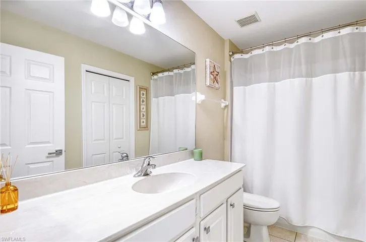 Bathroom featuring toilet, vanity, tile patterned flooring, and a shower with curtain