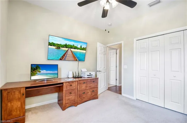 Home office with light carpet, ceiling fan, and baseboards