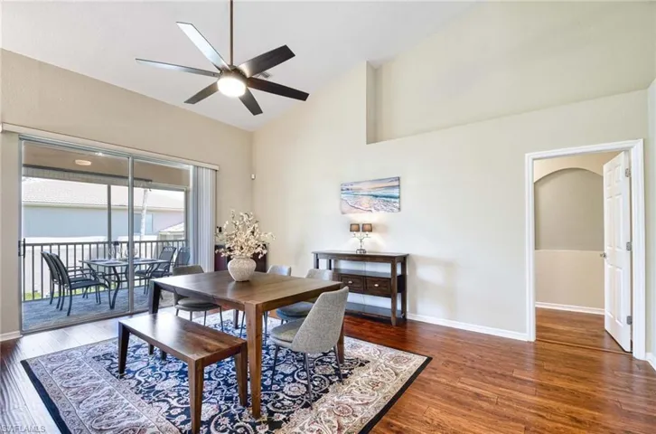 Dining room with ceiling fan, wood finished floors, baseboards, and high vaulted ceiling