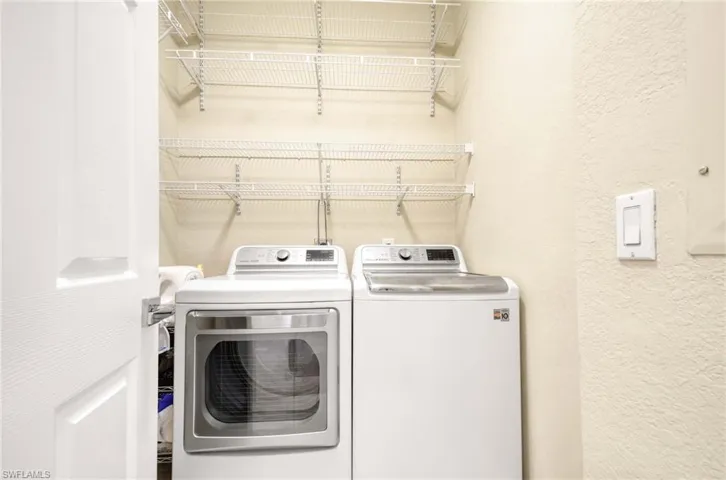 Laundry area with washing machine and dryer and a textured wall