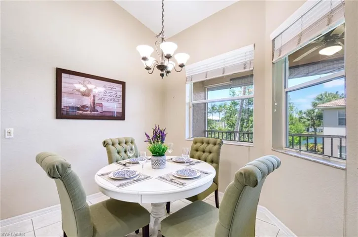 Dining area with a chandelier, baseboards, tile patterned flooring, and vaulted ceiling