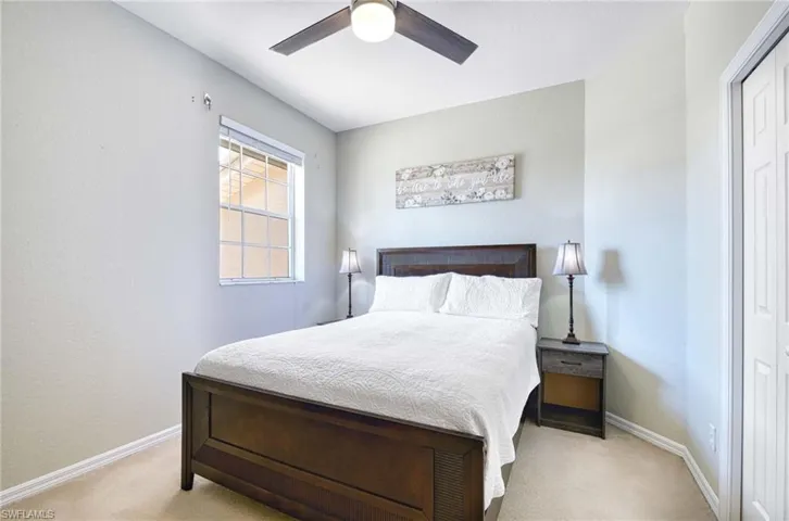 Bedroom featuring light colored carpet, baseboards, ceiling fan, and a closet
