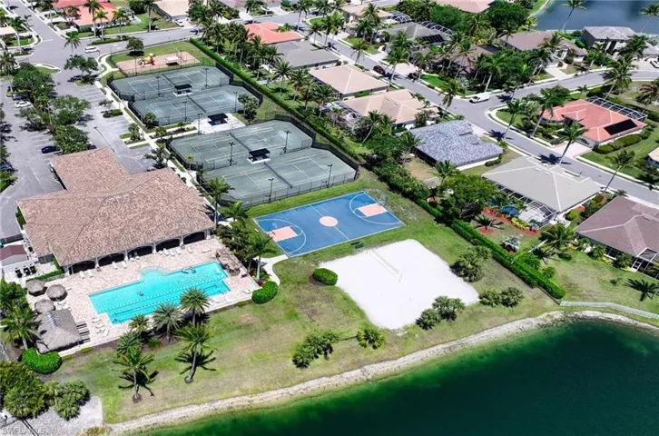 View of Main Clubhouse with lap pool, Tennis Courts, Basket ball, a nearby body of water, and nearby suburban area