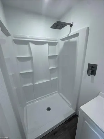 Bathroom with a shower, wood finished floors, and washer / clothes dryer