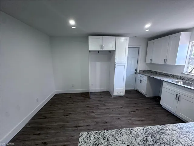 Kitchen with white cabinets, baseboards, recessed lighting, a sink, and dark wood finished floors