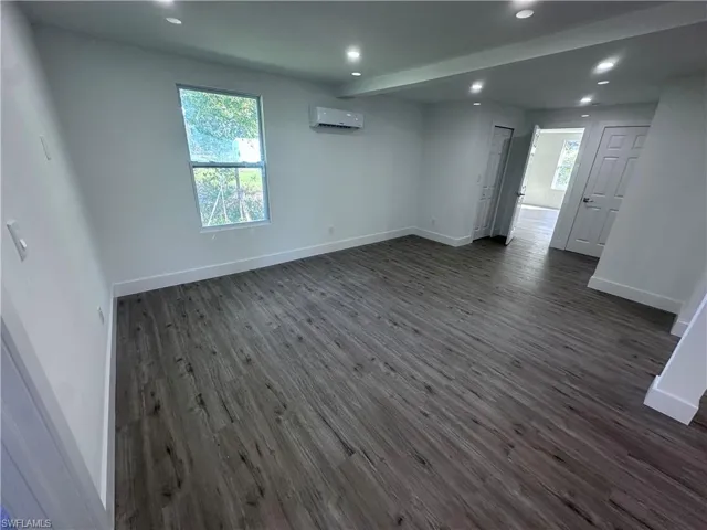 Empty room featuring a wall mounted AC, dark wood-style flooring, recessed lighting, and healthy amount of natural light