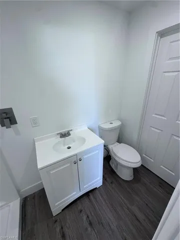 Bathroom featuring wood finished floors, vanity, toilet, and baseboards