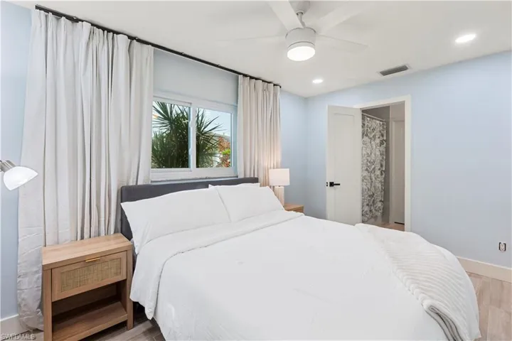 Bedroom with light wood-type flooring, a ceiling fan, recessed lighting, and connected bathroom