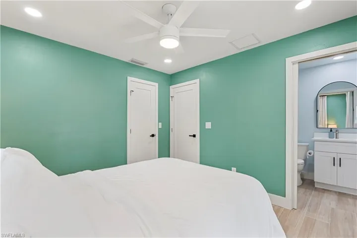 Bedroom featuring recessed lighting, light wood-type flooring, ceiling fan, and ensuite bath