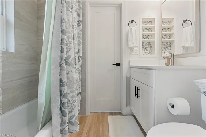 Full bathroom with vanity, shower / bath combination with curtain, and light wood-style floors