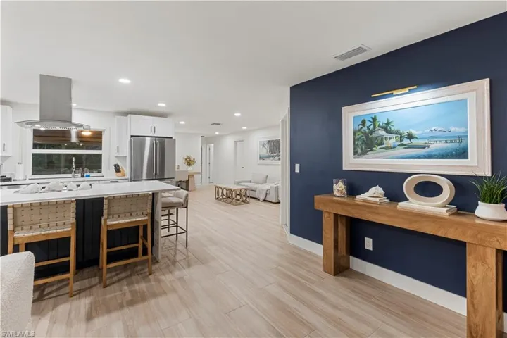 Kitchen featuring white cabinets, recessed lighting, a breakfast bar area, light wood-style floors, and island range hood