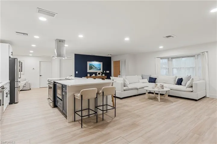 Kitchen with a center island with sink, a kitchen breakfast bar, recessed lighting, appliances with stainless steel finishes, and island exhaust hood
