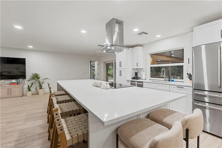 Kitchen featuring a kitchen breakfast bar, appliances with stainless steel finishes, white cabinets, light wood finished floors, and recessed lighting