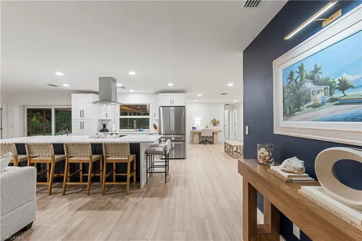 Kitchen featuring white cabinetry, stainless steel refrigerator, a kitchen breakfast bar, recessed lighting, and a large island