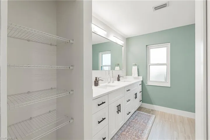 Bathroom with double vanity and light wood-style flooring