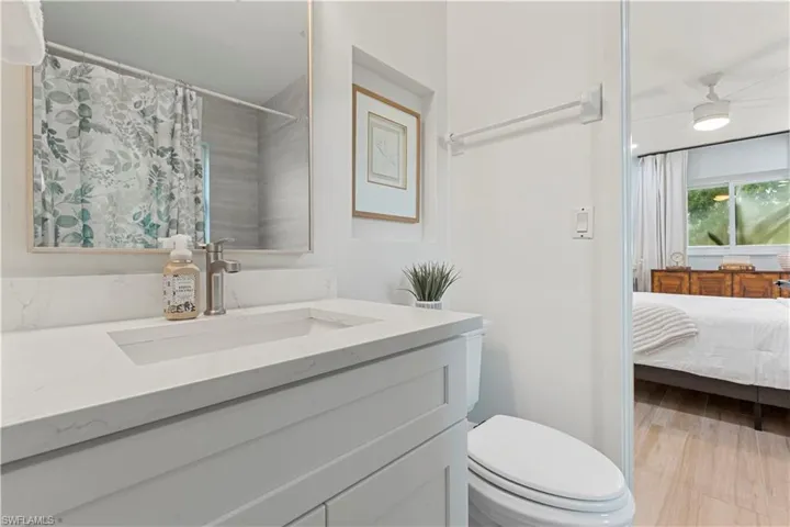 Bathroom with vanity, curtained shower, ensuite bathroom, light wood-style flooring, and a ceiling fan