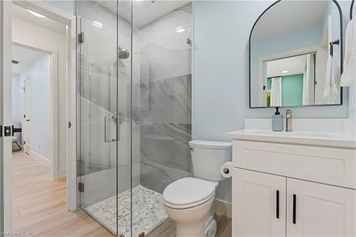 Full bath featuring light wood finished floors, a stall shower, and vanity