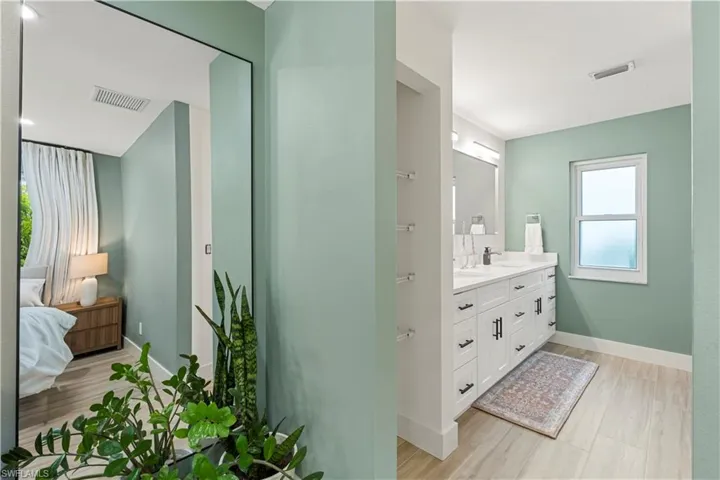 Full bath with double vanity, light wood-style flooring, and connected bathroom