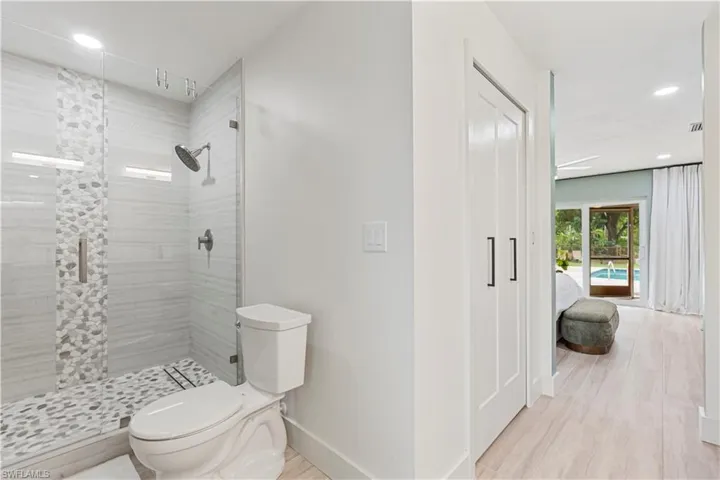 Ensuite bathroom with recessed lighting, a shower stall, and light wood-style floors