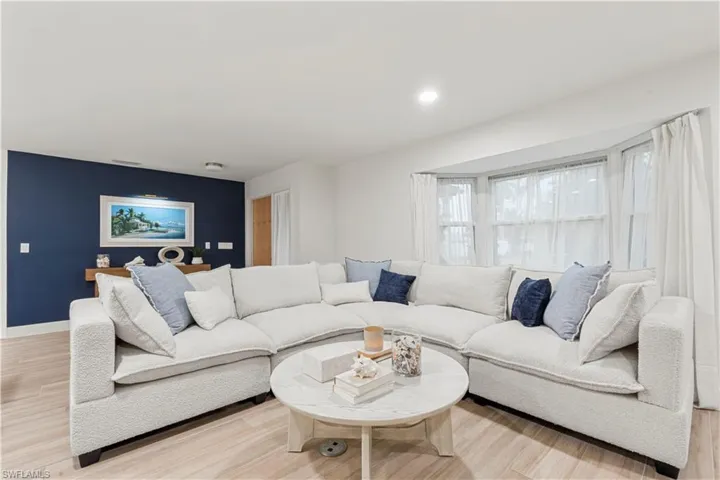 Living area with light wood finished floors and recessed lighting