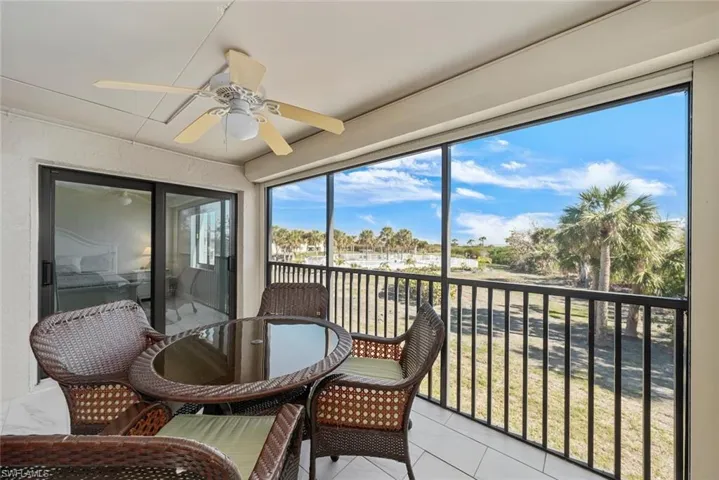 Screened balcony featuring white tiled flooring and an overhead ceiling fan