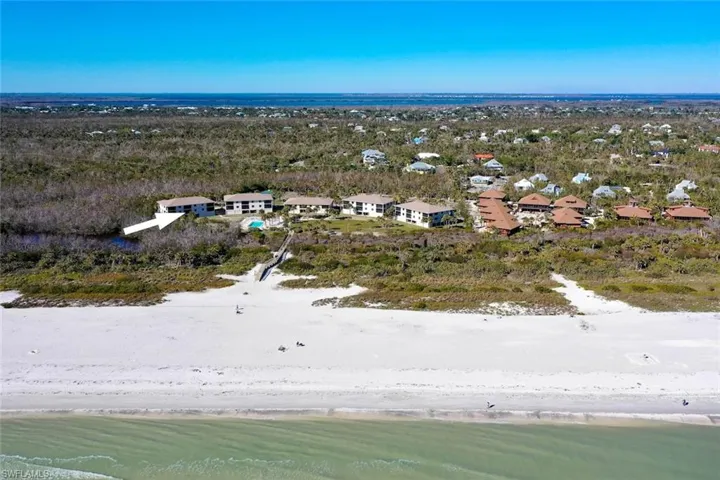 Coastal property featuring a white sand beach and verdant foliage